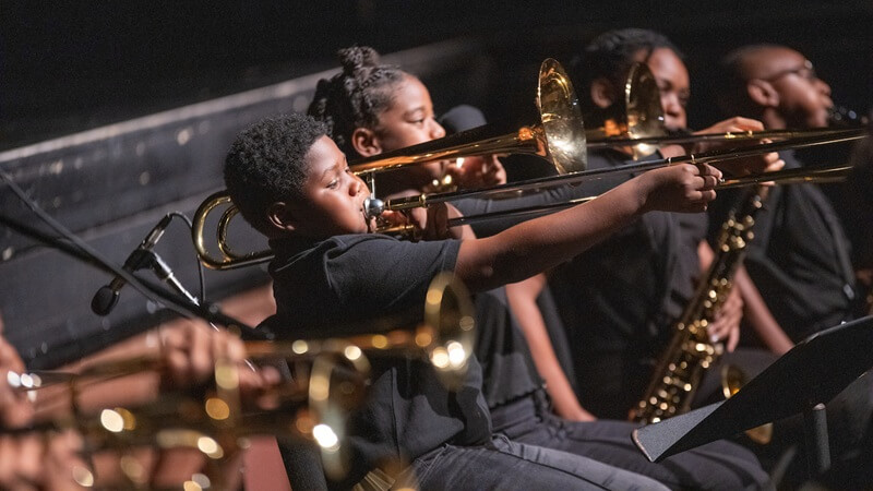 Children playing instruments on stage.